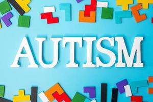 autism text med färgglada trä pusselbitar, geometrisk form block på blå bakgrund. begreppen hälsa, autistisk spektrumstörning och världsdagen för autism foto