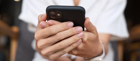 ung affärskvinna som håller och använder smartphone för sms, man skriver pekskärm mobiltelefon på kontor eller café. affärs-, livsstils-, teknik- och nätverkskoncept för sociala medier foto