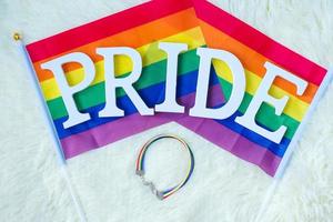 lgbtq, regnbågsflagga och armband på vit bakgrund. stödja lesbiska, homosexuella, bisexuella, transpersoner och queer-gemenskaper och pride-månadskoncept foto