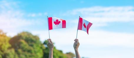 hand som håller Kanadas flagga på blå himmel bakgrund. Kanada dag och glada firande koncept foto
