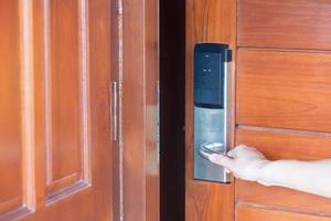 man håller handtaget på smart digitalt dörrlås medan du öppnar eller stänger dörren. teknik, el och livsstilskoncept foto