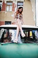 fantastiska långa ben med höga klackar flicka bär på hatt sitter på taket av gamla retro minivan. foto
