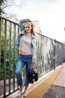 blond flicka bära på jeans med ryggsäck poserade på gatan. foto