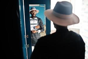 rik afrikansk man tittar på spegeln på garderoben på sin lägenhet. porträtt av framgångsrik svart man inomhus. foto