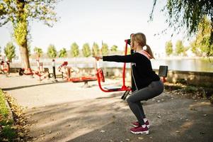 ung flicka tränar och tränar utomhus på gatusimulatorer. sport, fitness, street workout koncept. foto