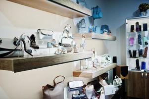 enormt utbud av kvinnliga skor och väskor i olika färger på hyllorna i butiken. foto