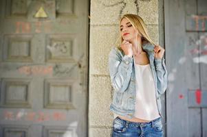 blond flicka slitage på jeans jacka poserade på gatan. foto