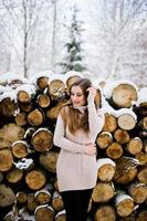 vacker brunett flicka i vinter varma kläder. modell på vintertröja nära stubben. foto