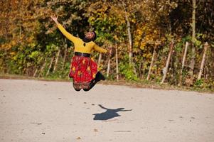 afrikansk amerikansk flicka på gul och röd klänning på gyllene höst höst park. foto