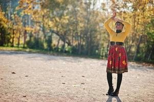 afrikansk amerikansk flicka på gul och röd klänning på gyllene höst höst park. foto