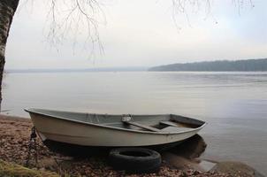 båt på stranden av en lugn sjö, landskap i neutrala färger foto