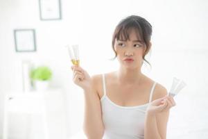vackert porträtt ung asiatisk kvinna som håller och presenterar kräm- eller lotionprodukt, skönhetsasiatisk flicka visar kosmetisk makeup och återfuktande för hudvård, hälsovård och wellness-koncept. foto