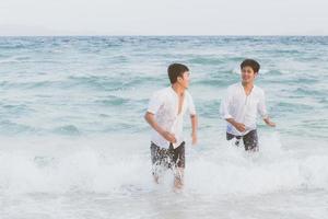 homosexuella porträtt ungt asiatiskt par springer med glada tillsammans på stranden på sommaren, asien gay turism för fritid och koppla av med lycka i semestern till sjöss, hbt juridiskt koncept. foto