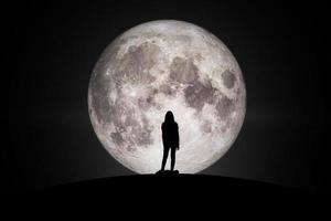 siluett av kvinnor som tittar på månen med hoppuppfyllelse i kärlek. delar av denna bild från nasa. foto