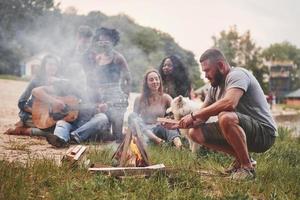 för mycket rök. grupp människor har picknick på stranden. vänner har kul på helgen foto