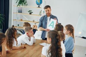 visar ett brev. grupp barn elever i klassen i skolan med lärare foto