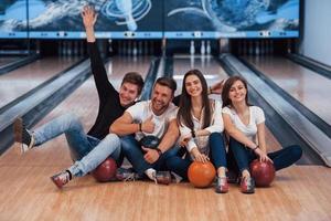 visar gester. unga glada vänner har kul i bowlingklubben på sina helger foto