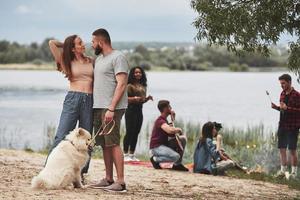 kyss kommer att hända. grupp människor har picknick på stranden. vänner har kul på helgen foto