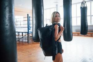 många boxningssäckar. vuxen kvinna med hörlurar i gymmet foto