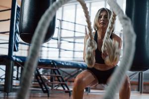 närbild. blond sport kvinna har träning med rep i gymmet. stark hona foto
