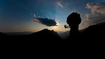 siluett av en bergsklättrare som går ner på repet efter att ha klättrat vid solnedgången foto