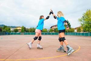 två sport tjej i en tennis rollerblade ger dig klappa i handen foto