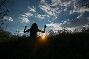 kvinna gör yoga på ängen vid soluppgången foto