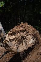 närbild av bulldozermaskin som gräver marken och tar bort sand för utgrävningsändamål foto