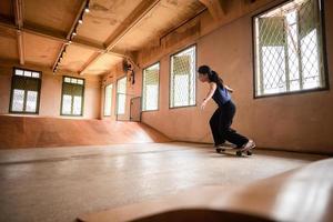 skater kvinna person som spelar skateboard i sportgym, ung asiatisk kvinna är glad och rolig med skateboard livsstil i staden, tonårs hipster kvinnligt trendigt mode foto