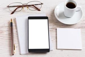 anteckningsbok med glasögon, penna, smart telefon och kaffekopp