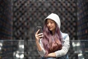 vacker asiatisk kvinna, tonåring, flicka som spelar mobiltelefon med roligt och glad på fritiden, semester foto