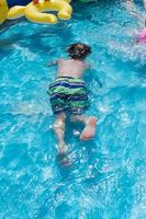 ung pojke simmar under vattnet med glasögon i poolen foto