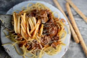 gaffel insvept med spaghetti nudlar över tallrik spagetti med köttbullar foto