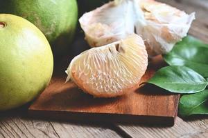 pomelofrukt på träplattabakgrund, färsk grön pomelo skalad och blad från pomeloträd, pummelo, grapefrukt på sommaren tropisk frukt i thailand foto