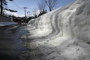 hög med snö bredvid en väg i kusatsu onsen, Japan foto