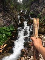 synvinkel av en vandrare med vandringsstav framför en liten bergsflod foto