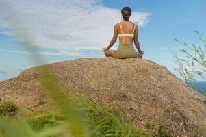 vacker asiatisk kvinna i sportkläder gör yoga på bergstoppen vid havet efter vandring, resor och meditationskoncept. foto