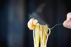 varm och kryddig spagetti med räkor och gaffel över svart bakgrund - italiensk mat med människor koncept foto