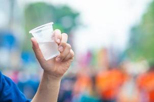 nordthailändsk man dricker färskt kallt vatten i plastglas under deltagande utomhusaktivitet i mycket varm dag iförd skjorta i nordlig thailändsk stil foto