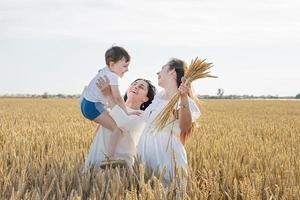 lycklig familj på tre personer, mor och två barn som går på vetefält foto