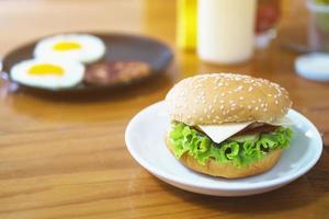 hamburgerfrukost med oskärpa stekta ägg och krydda bakgrund på träbord - utsökt snabbmat frukost koncept foto