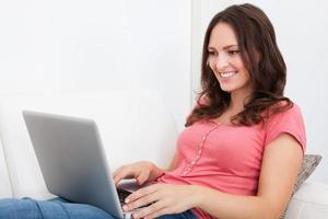 kvinna sitter på soffan med laptop foto