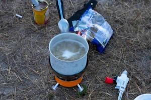 pasta i sked och kokande vatten i en kastrull, turistmat i naturen. foto