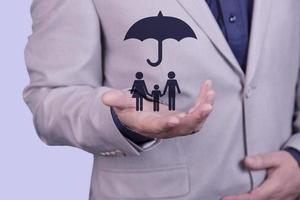 en affärsman håller ett paraply på sin hand, över ett familjekoncept, för skydd, säkerhet, ekonomi och försäkring. foto