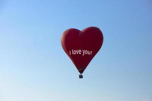 luftballong, röd ballong i form av ett flygande hjärta med texten, jag älskar dig. foto