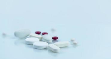 selektivt fokus på hög med vita och röda sockerdragerade tabletter piller på suddig bakgrund. apotek bakgrund. läkemedelsindustri. hälsovård och farmakologi koncept. droger på vit bakgrund foto