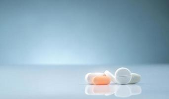 apoteksprodukt. hög med orange och vita tabletter piller på lutning bakgrund. olika storlekar och form tabletter piller. läkemedelsindustri. medicin på sjukhus. detaljhandelsmarknaden för läkemedel. foto