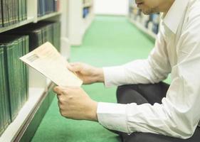 en man läser förbi tidningar nära bokhyllans bibliotek foto