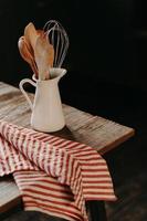 vertikal bild av vintage köksredskap i vit keramikburk på träbord. hem köksinredning. köksutrustning för matlagning. husgeråd foto