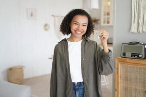 afroamerikansk ung flicka som visar nycklarna till det nya huset. fastighetsservice reklam, flytt foto